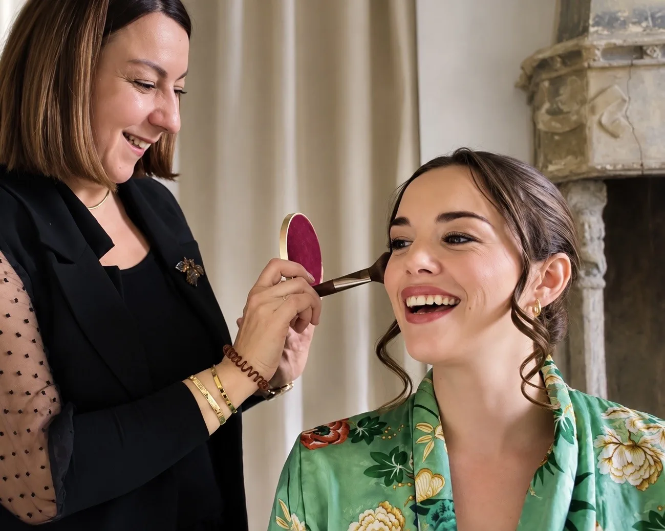 Céline Giraud, souriante, applique le blush d'une mariée pendant la séance